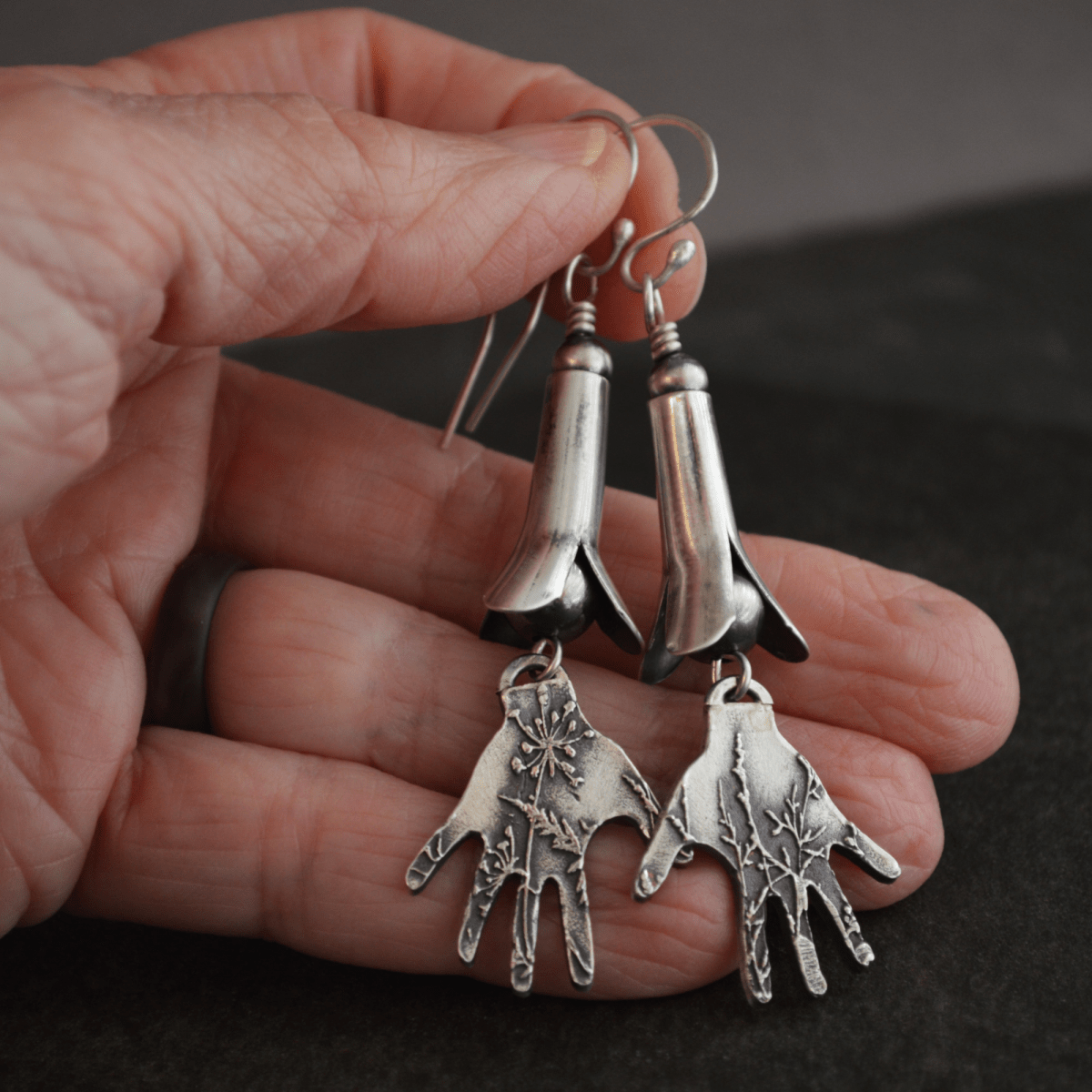 A Hand Holding Silver Squash Blossom Earrings With Hands Textured with a Prairie Design - Gayle Dowell